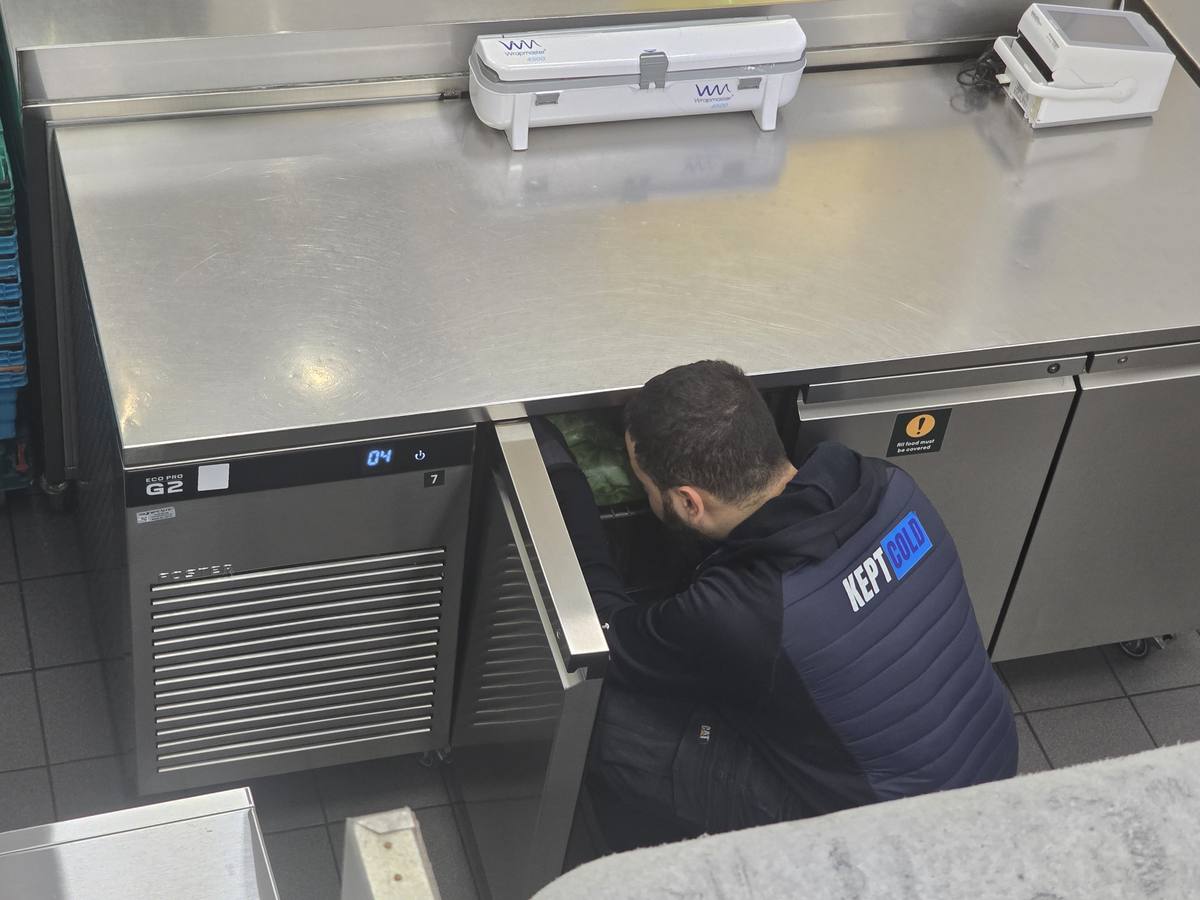 Kept Cold engineer servicing a Foster prep counter in a commercial kitchen